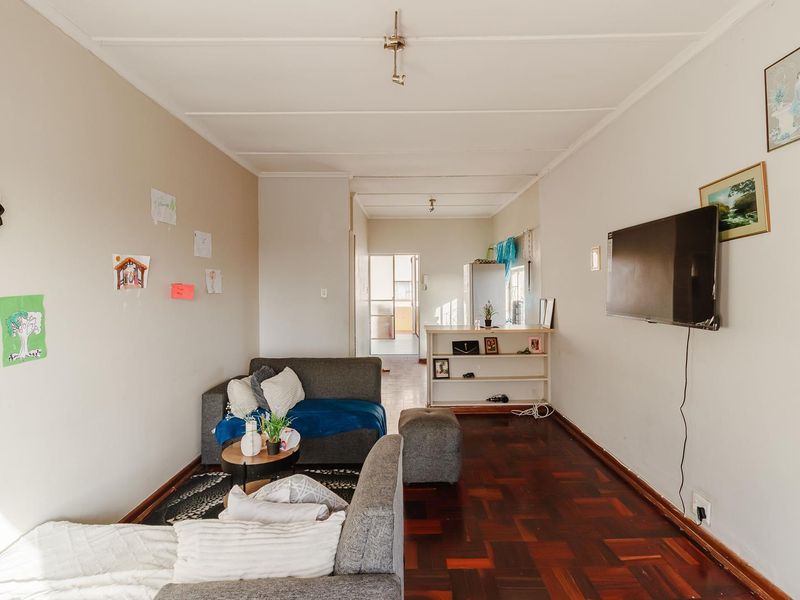 Open plan living area featuring traditional parquet flooring and neutral wall finishes, providing a functional space with direct access to the kitchen area.