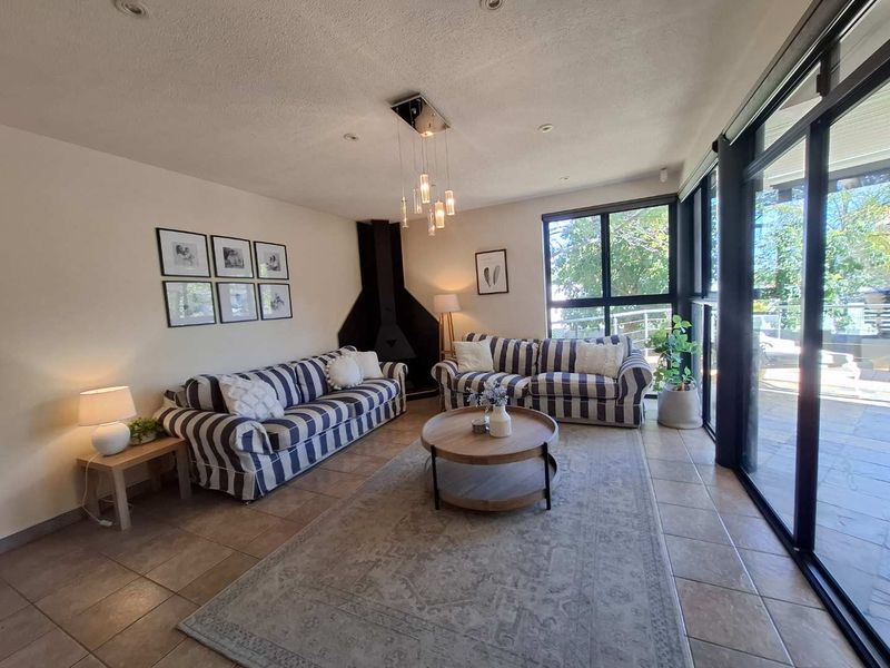 A bright living room featuring a unique suspended fireplace, tiled flooring, and large sliding glass doors that provide ample natural light.