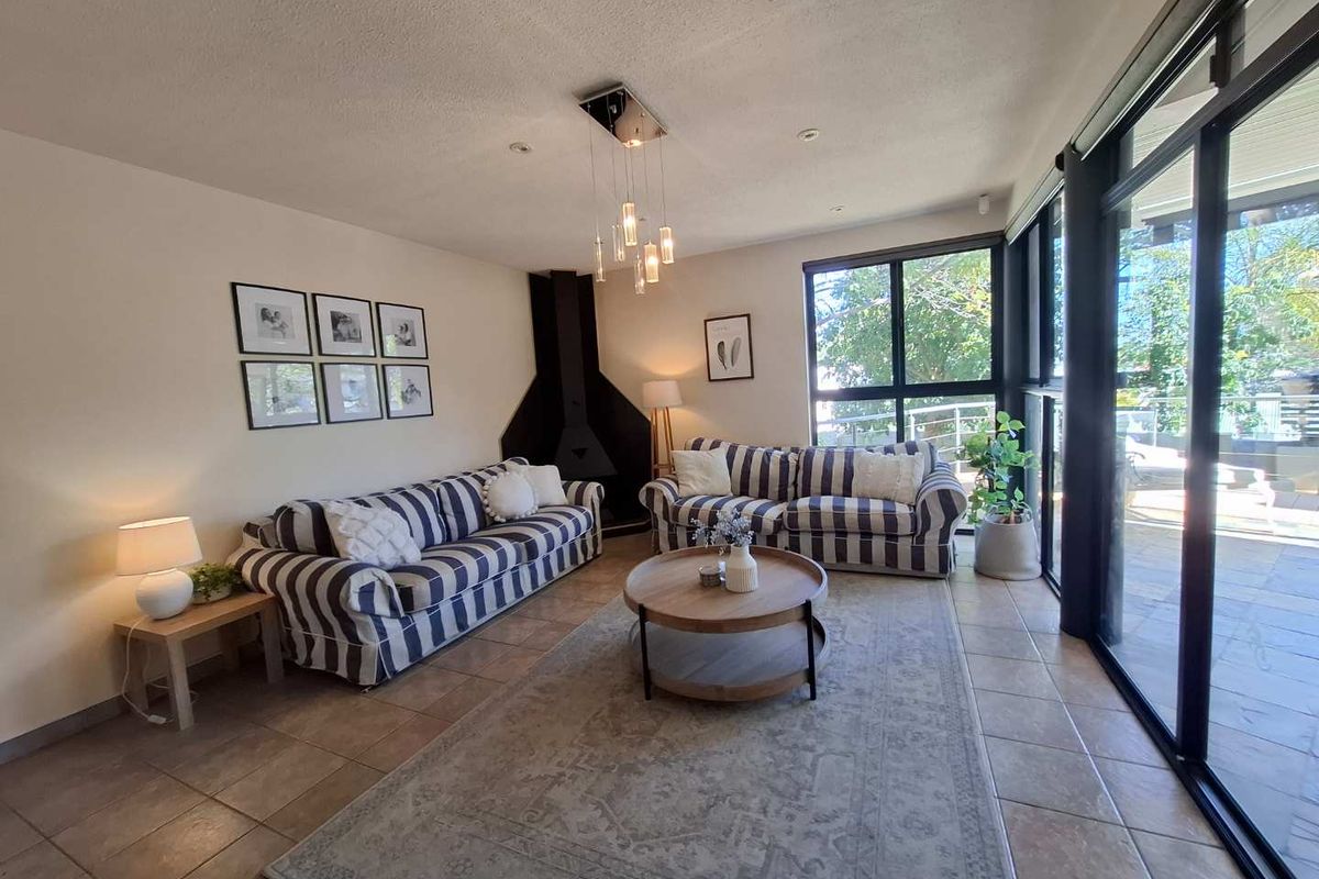 A bright living room featuring a unique suspended fireplace, tiled flooring, and large sliding glass doors that provide ample natural light.