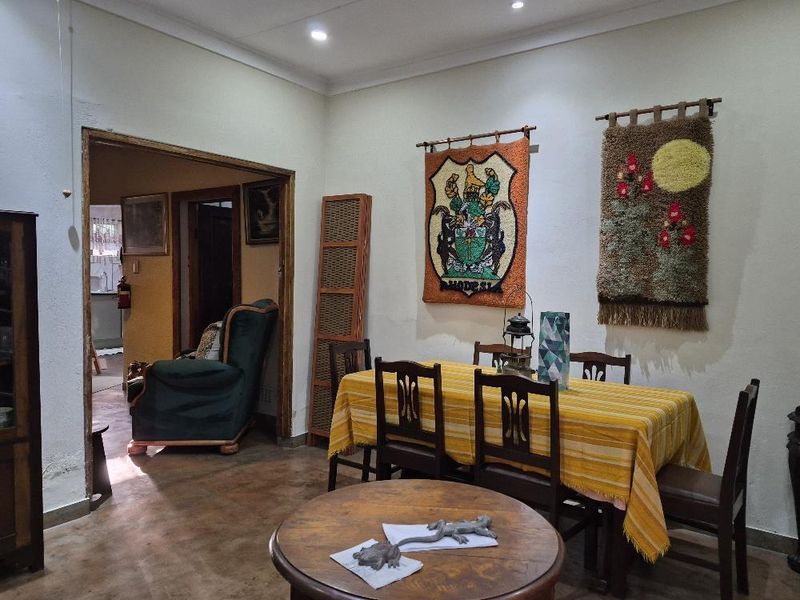 A dining room featuring concrete flooring and recessed downlighting, with an open doorway leading to an adjacent living area.