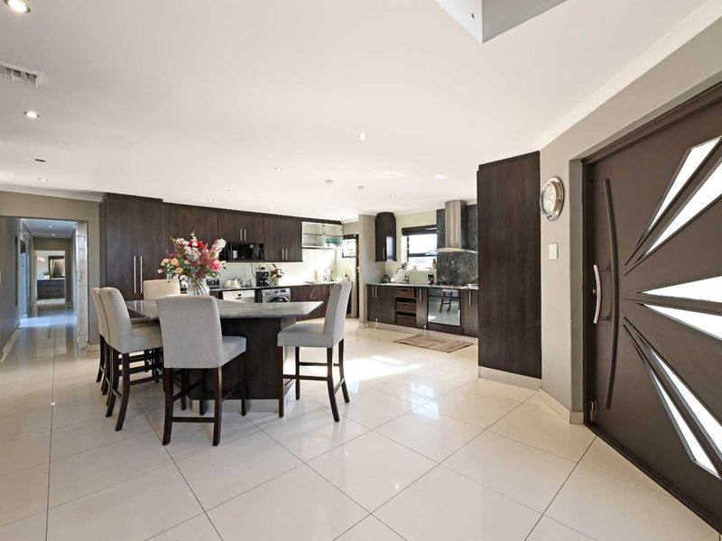 Spacious open-plan kitchen featuring dark wood cabinetry, a central island with breakfast bar seating, and modern tiled flooring throughout.