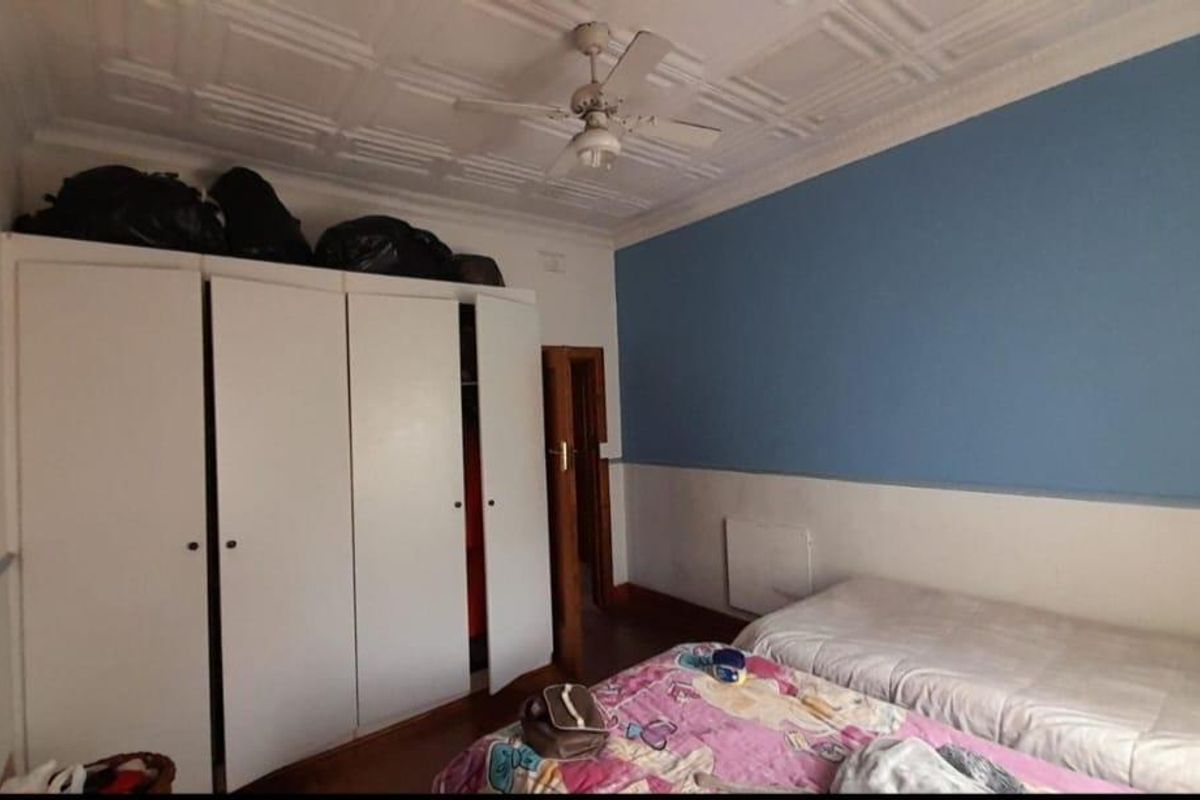 A bedroom featuring built-in wardrobes, a ceiling fan, and a decorative pressed metal ceiling.