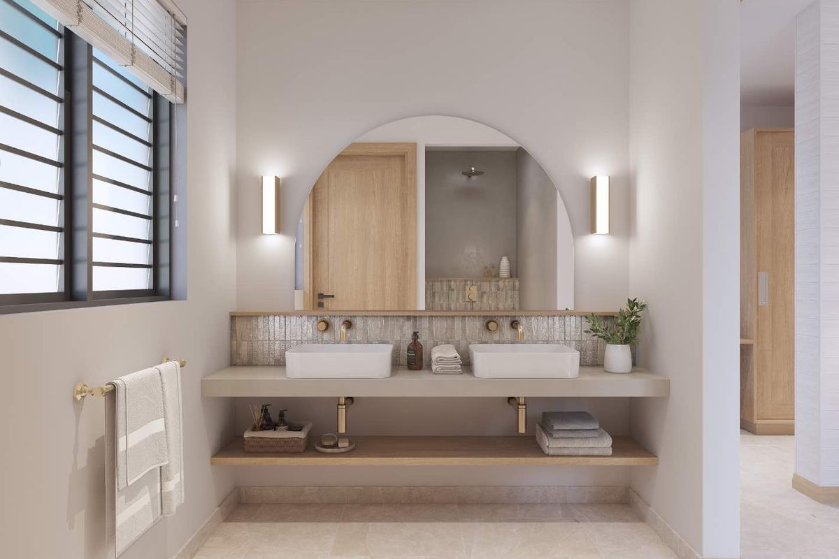 Modern bathroom featuring a double vanity with vessel sinks, brass fixtures, an arched mirror, and a lower timber shelf for storage.