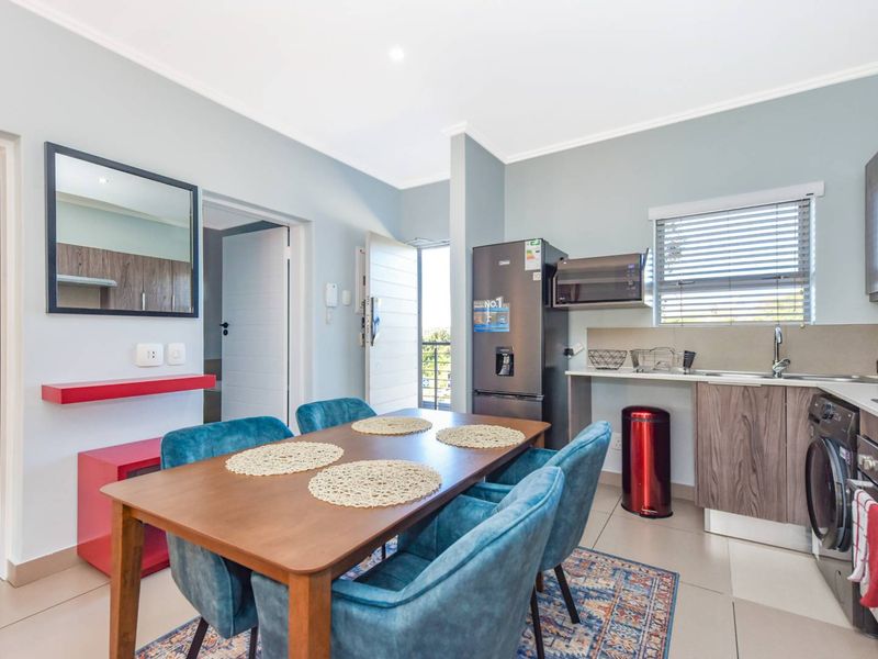 Modern open-plan living area featuring a well-appointed kitchen with built-in cabinetry, integrated appliances, and tiled flooring, seamlessly flowing into the dining space.