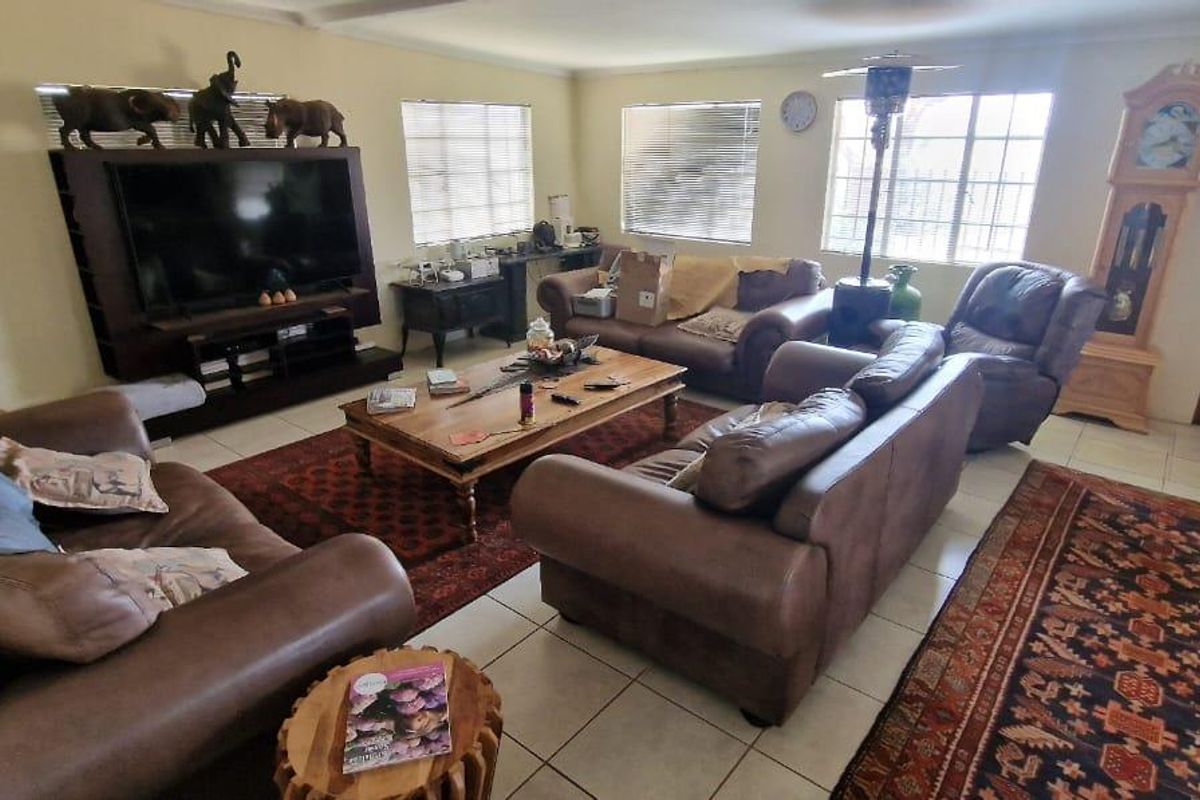 Spacious living room featuring tiled flooring, large windows providing natural light, and coved ceiling details.