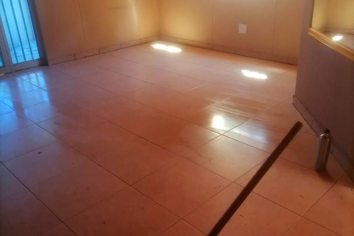 An empty interior room featuring tiled flooring and a sliding glass door, providing a blank canvas for potential renovation or restyling.