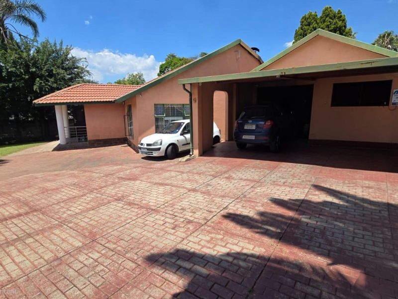 Front exterior view of the house featuring a paved driveway, covered carport, and traditional tiled roof architecture.