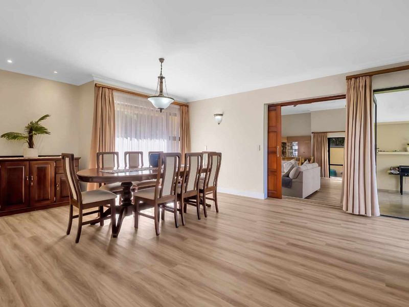 Spacious dining room featuring light-toned laminate flooring, recessed downlighting, and a large sliding wooden door providing access to the adjacent living area.