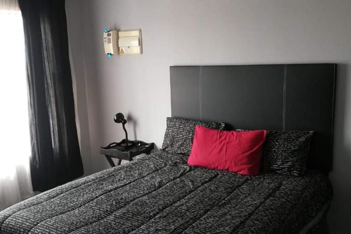 A bedroom featuring tiled flooring, dark window treatments, and a wall-mounted electrical distribution board.