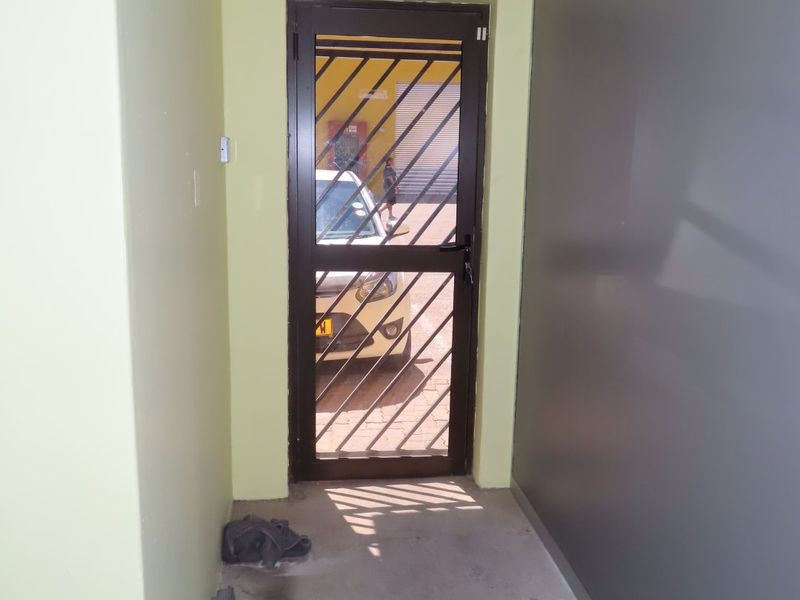 A functional entry area featuring a secure metal gate and a mounted security camera, providing access to the exterior parking area.