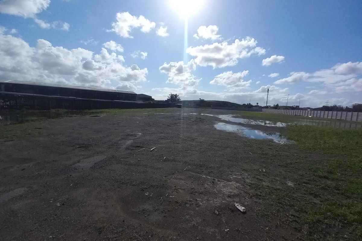 A large, undeveloped industrial plot featuring unpaved ground and perimeter fencing, suitable for future development or storage.