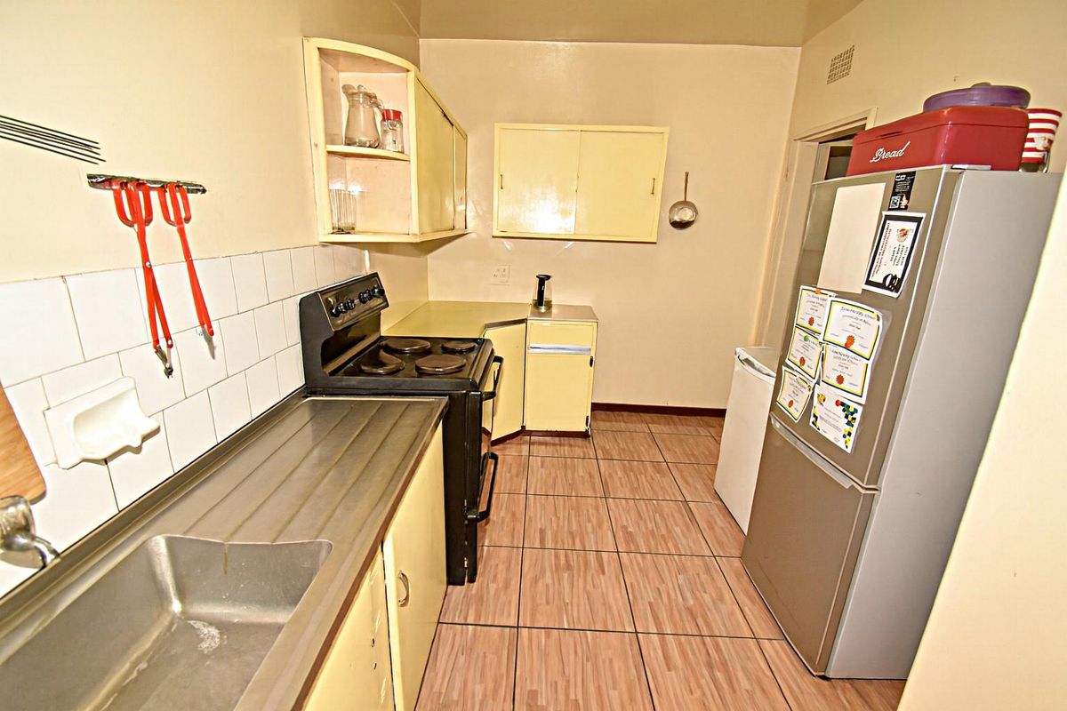 A compact kitchen featuring dated cabinetry, a built-in stove, and tiled flooring, offering a functional space with potential for modernization.