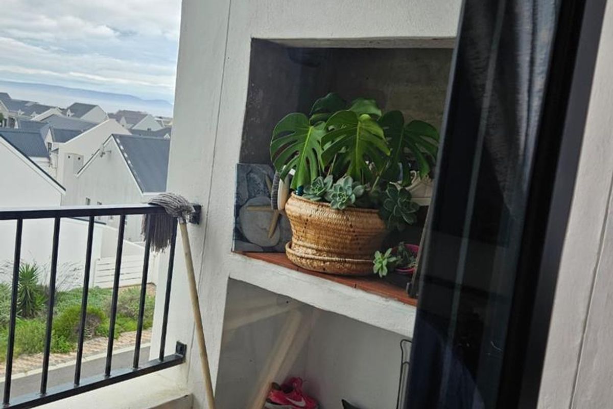 A balcony area featuring a built-in shelving unit and metal balustrade, offering an outdoor space with views of the surrounding neighborhood.
