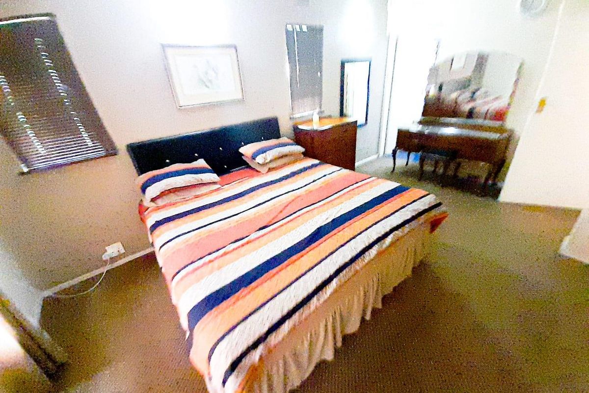 A bedroom featuring carpeted flooring, a window with fitted blinds, and neutral wall finishes.
