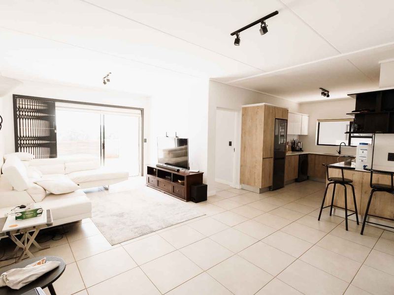 Spacious open-plan living area featuring tiled floors, modern kitchen cabinetry with an island, and large sliding doors leading to an outdoor space.