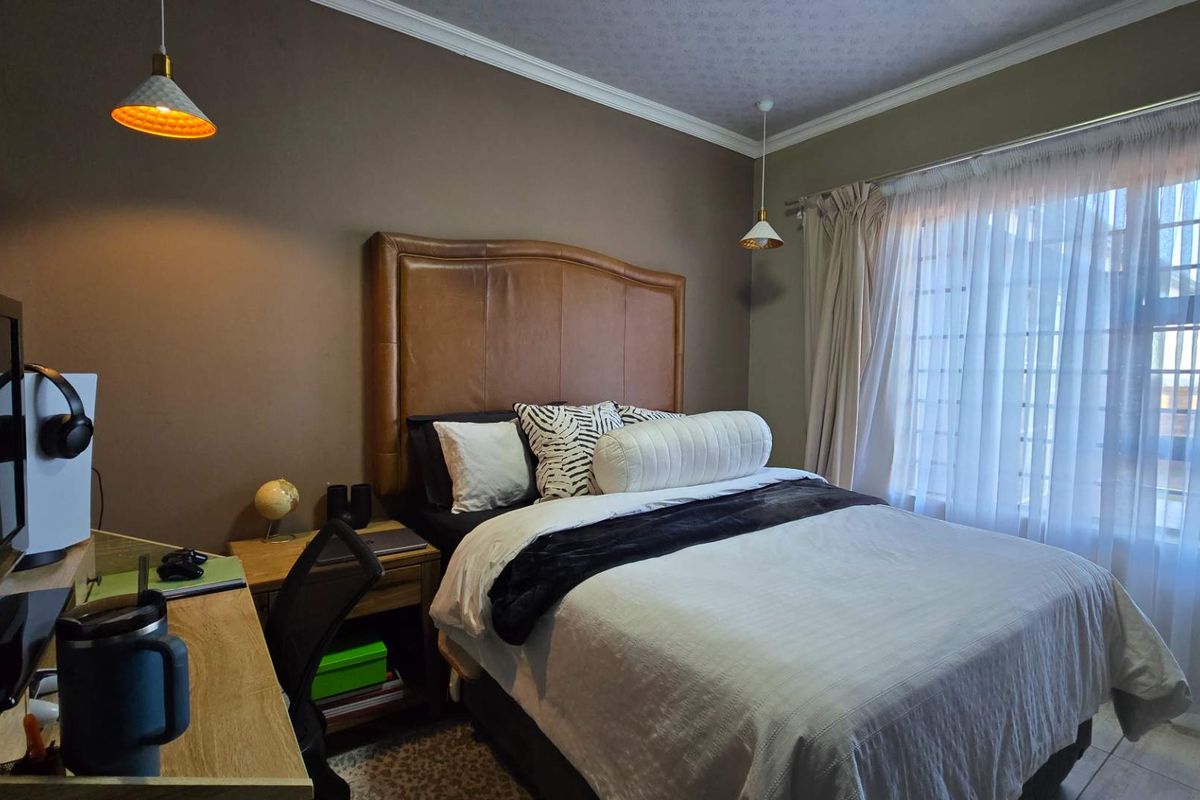 A well-maintained bedroom featuring neutral wall tones, decorative coving, and pendant lighting, providing a comfortable and functional sleeping space.
