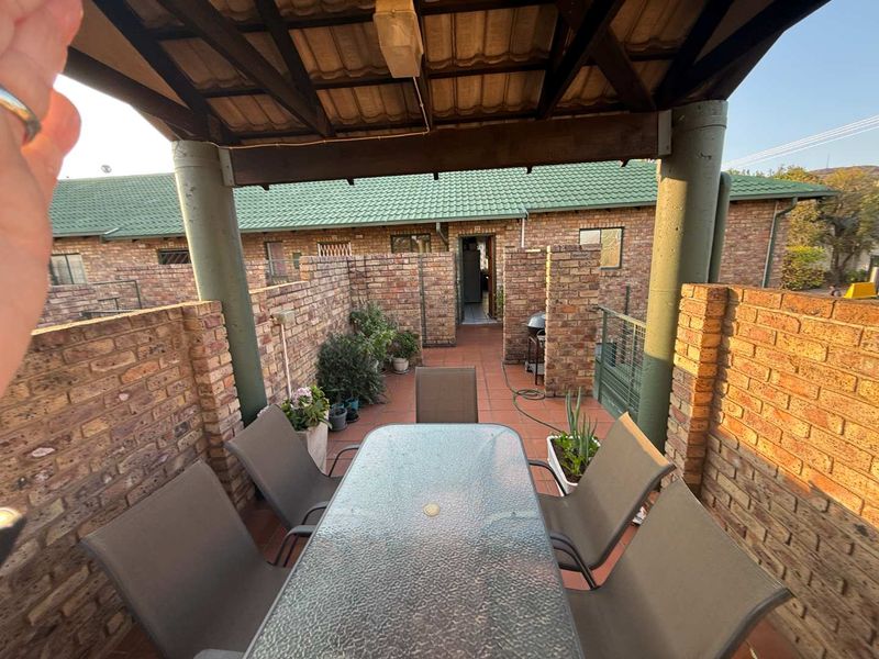 A covered outdoor patio area featuring brick walls, tiled flooring, and a roof structure, providing a private space for outdoor dining.