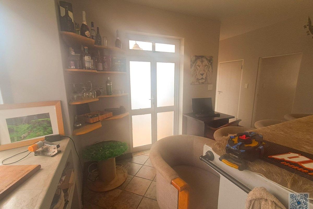 A functional living area featuring tiled flooring, built-in corner shelving, and a glass-paneled exterior door providing natural light.