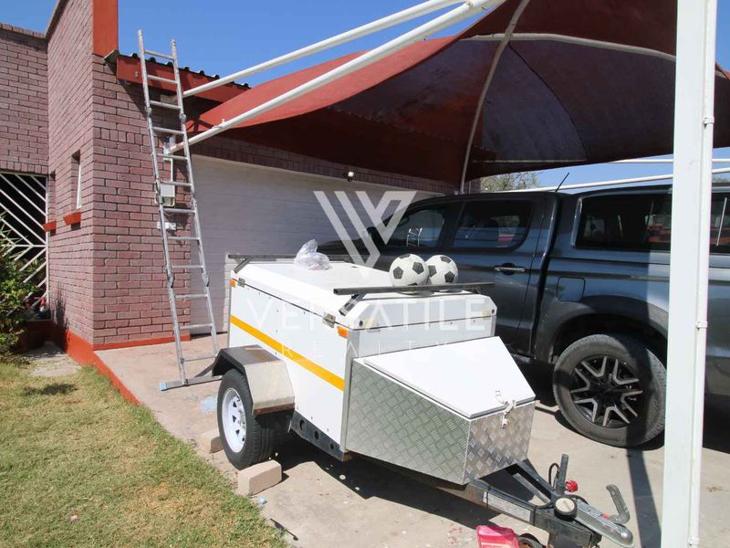 Front exterior view of the property featuring a brick facade, garage access, and a shade sail structure over the driveway area.