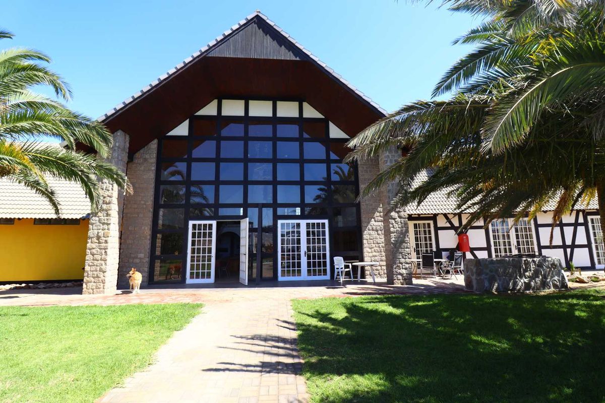 A striking exterior view of a large, timber-framed building with expansive glass paneling, stone masonry accents, and a well-maintained lawn.