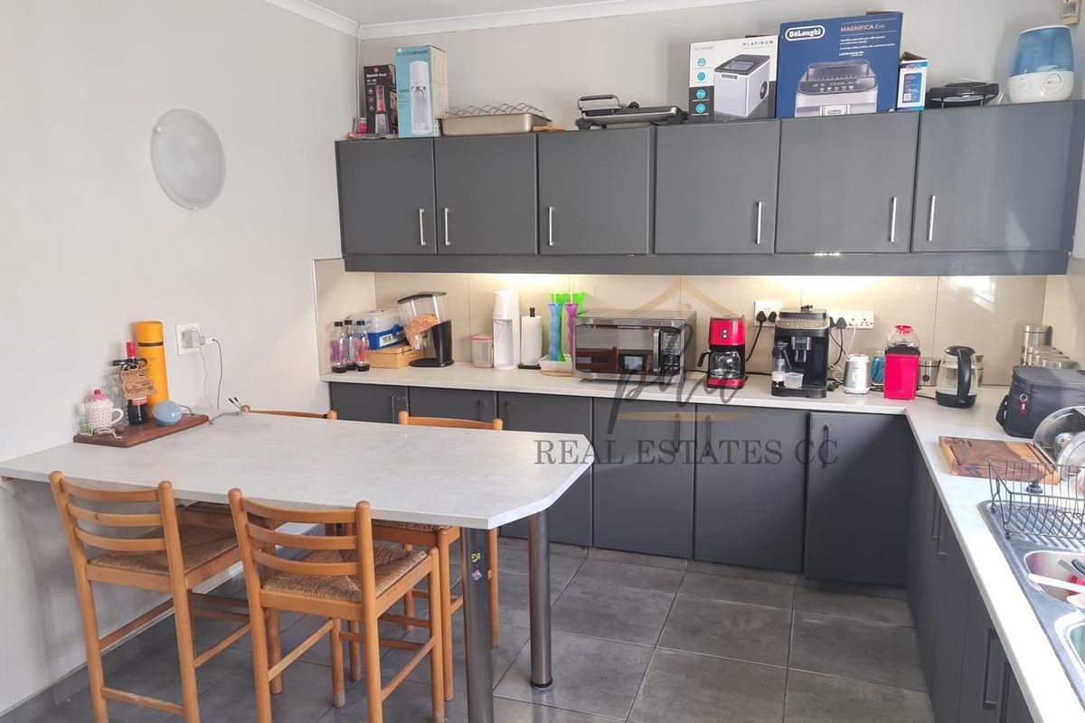 Modern kitchen featuring dark grey cabinetry, light countertops, tiled flooring, and an integrated breakfast bar area.
