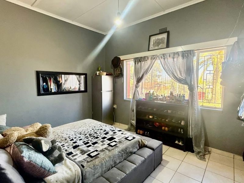 A bedroom featuring tiled flooring, a window with security bars, and coved ceiling details.