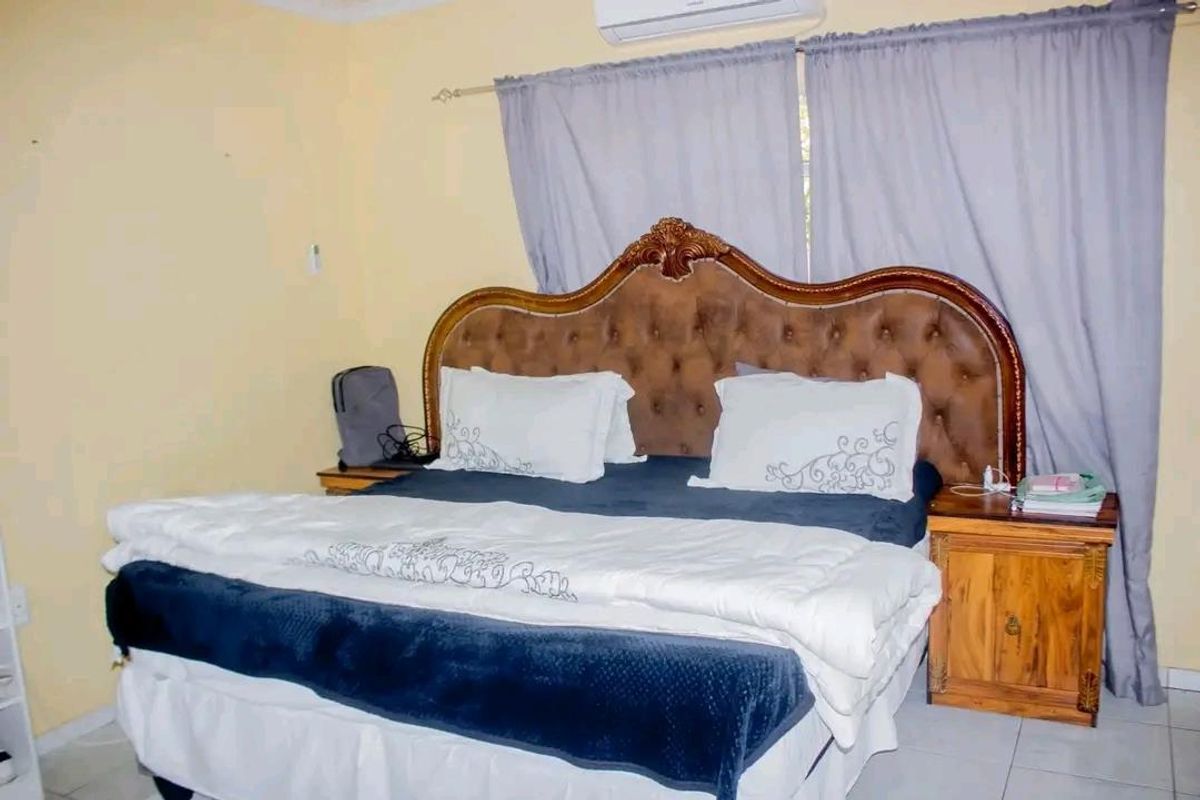 A bedroom featuring a wall-mounted air conditioning unit, tiled flooring, and neutral wall tones.