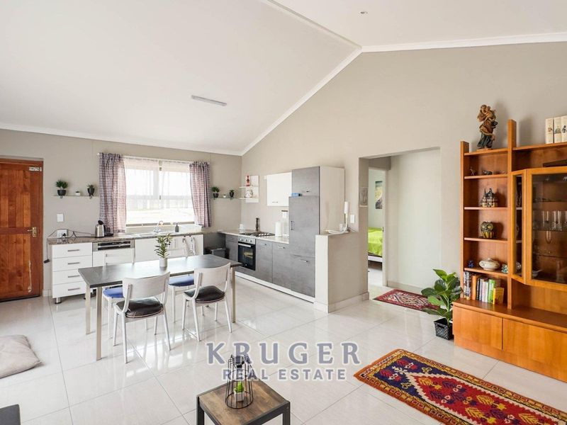 Spacious open-plan living and kitchen area featuring vaulted ceilings, modern cabinetry, integrated appliances, and neutral tiled flooring throughout.