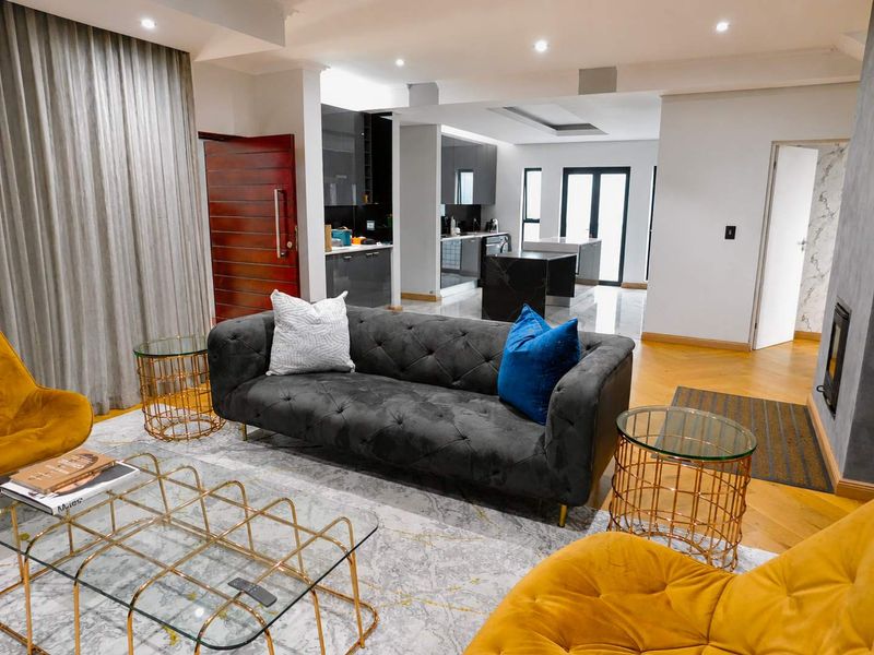 Modern open-plan living area featuring a seamless transition between the lounge and a contemporary kitchen with high-gloss cabinetry and a central island.