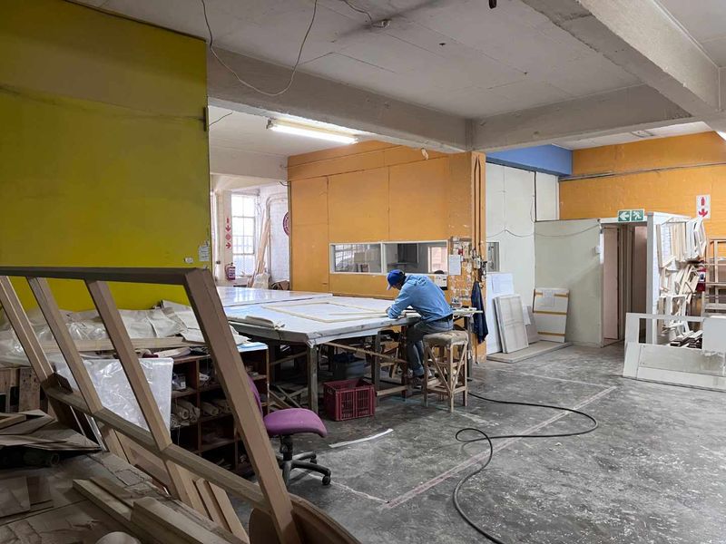 Industrial utility space featuring exposed concrete ceilings, fluorescent lighting, and concrete flooring, suitable for workshop or storage use.