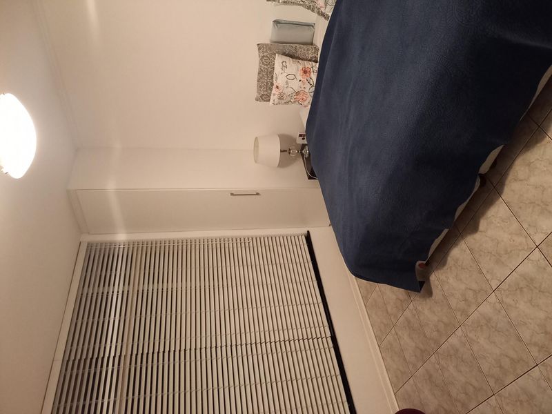 A functional bedroom featuring tiled flooring, a built-in wardrobe, and venetian blinds for privacy.