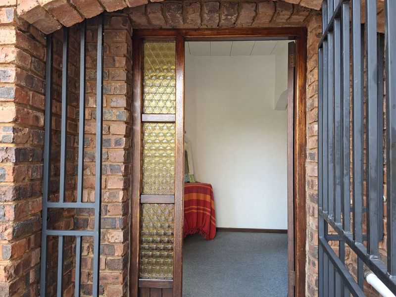 Entrance view featuring a rustic brick archway, security gate, and a decorative textured glass sidelight leading into the home.