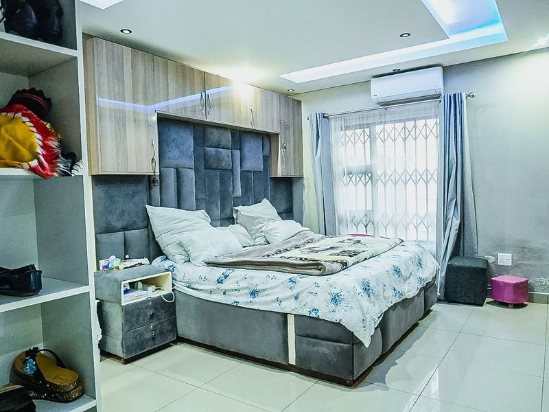 A bedroom featuring built-in cabinetry, recessed ceiling lighting, tiled floors, and a wall-mounted air conditioning unit.