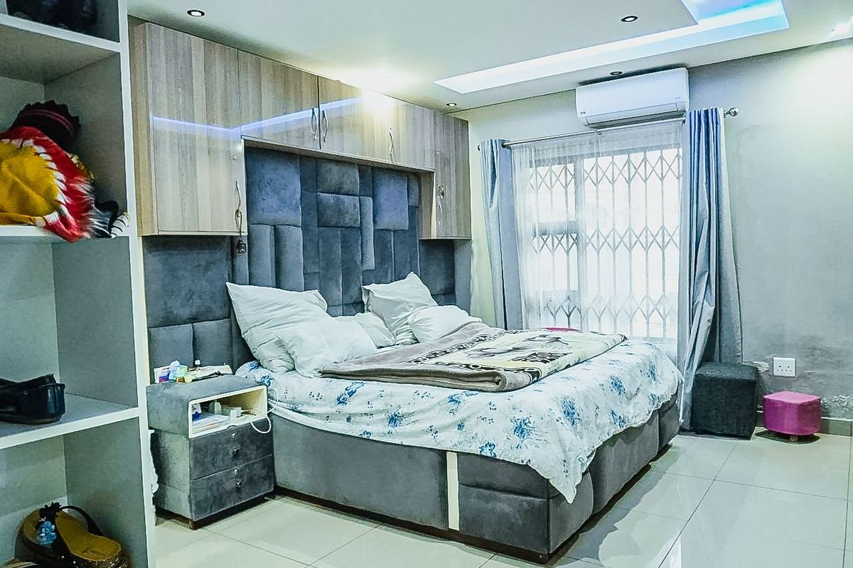 A bedroom featuring built-in cabinetry, recessed ceiling lighting, tiled floors, and a wall-mounted air conditioning unit.