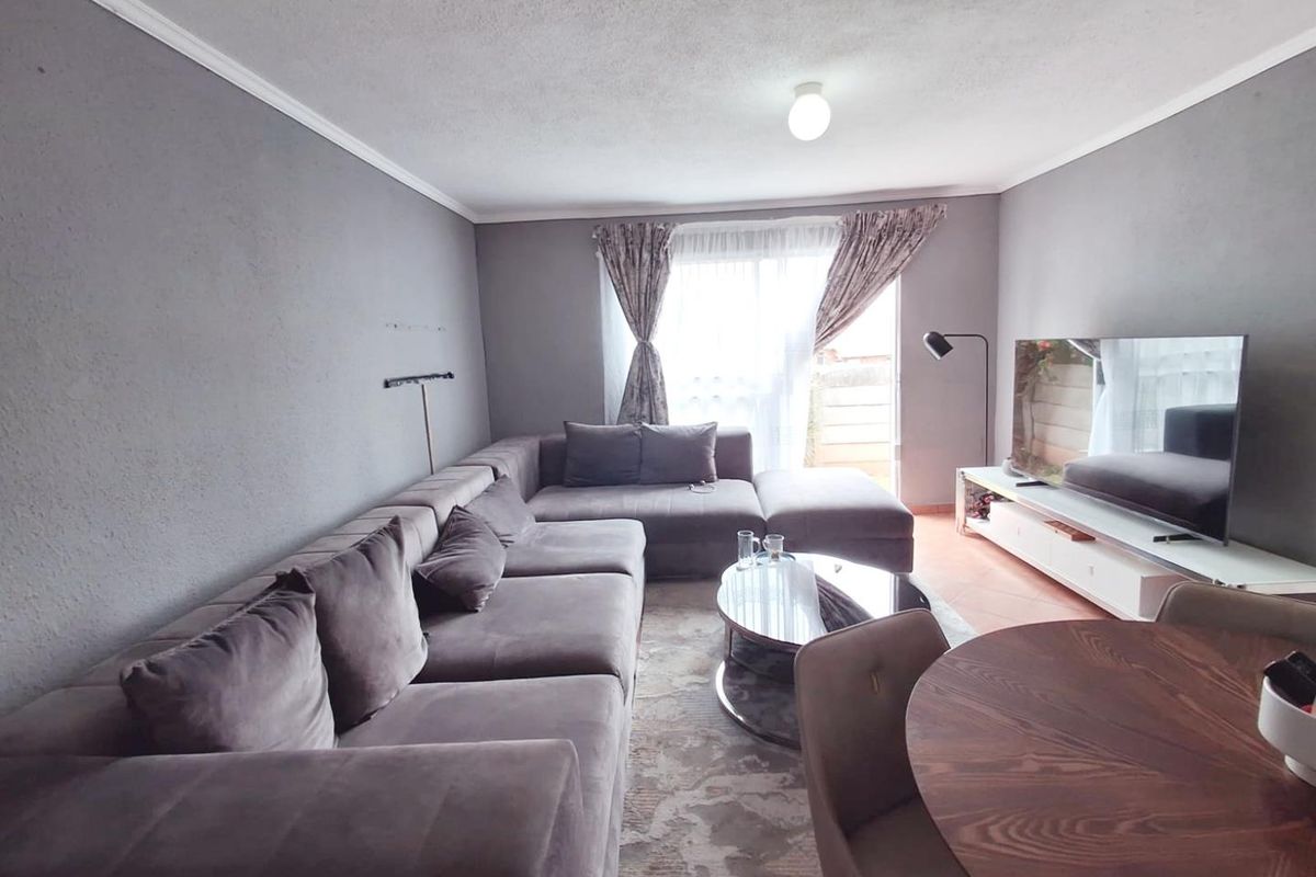 A comfortable living room featuring tiled flooring and a sliding glass door that provides access to the outdoor area.