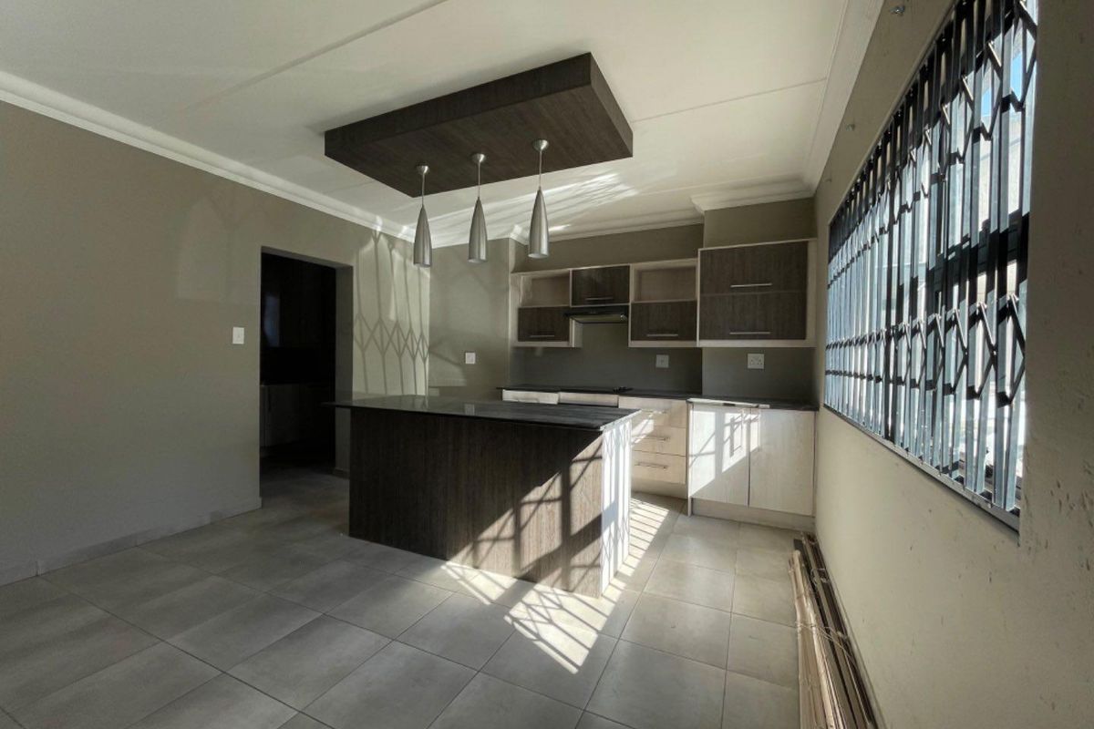 Modern kitchen featuring a central island, built-in cabinetry, extractor fan, and tiled flooring, offering a clean and functional space.