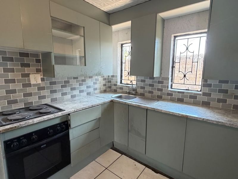 A compact kitchen featuring built-in cabinetry, a tiled backsplash, and integrated cooking appliances, offering a functional layout ready for cosmetic updates.