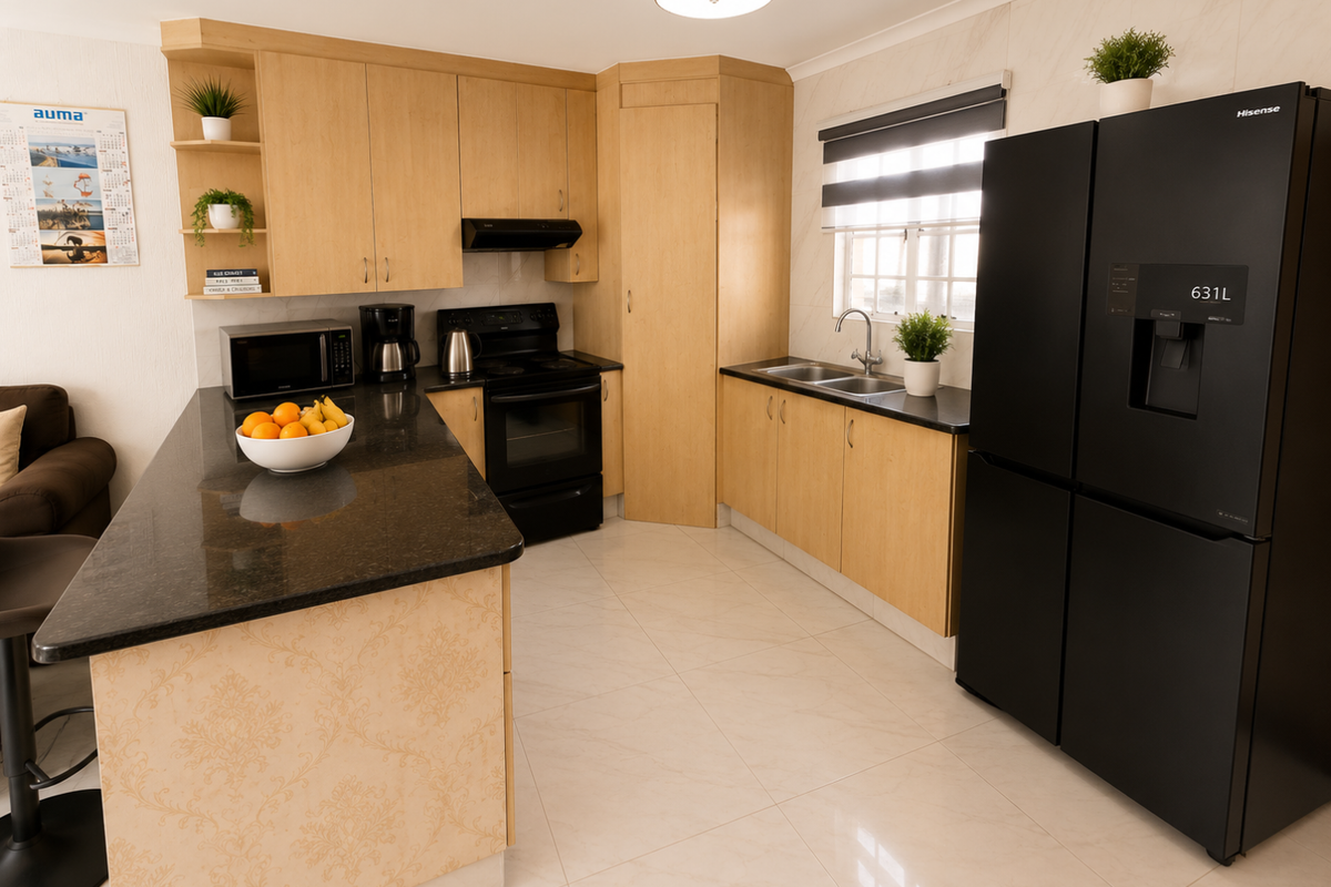 Modern kitchen featuring light wood cabinetry, dark granite countertops, a central island, and tiled flooring, offering a functional and well-maintained cooking space.