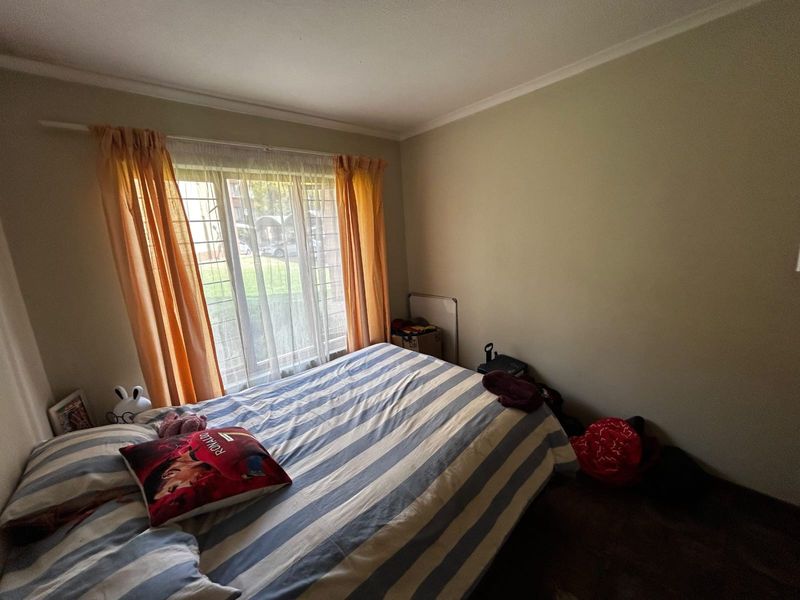 A standard bedroom featuring a window with security bars and simple cornice detailing.