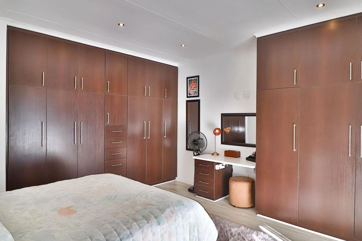 A well-maintained bedroom featuring extensive floor-to-ceiling built-in wooden cabinetry and integrated vanity storage, providing ample organized space.