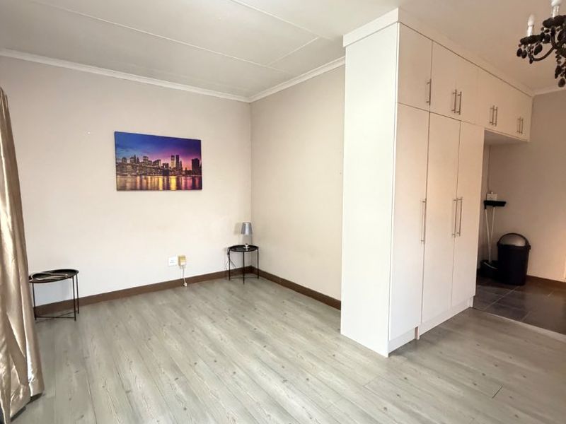 A bright and spacious living area featuring modern laminate flooring and ample built-in cupboard storage, offering a clean and versatile living space.