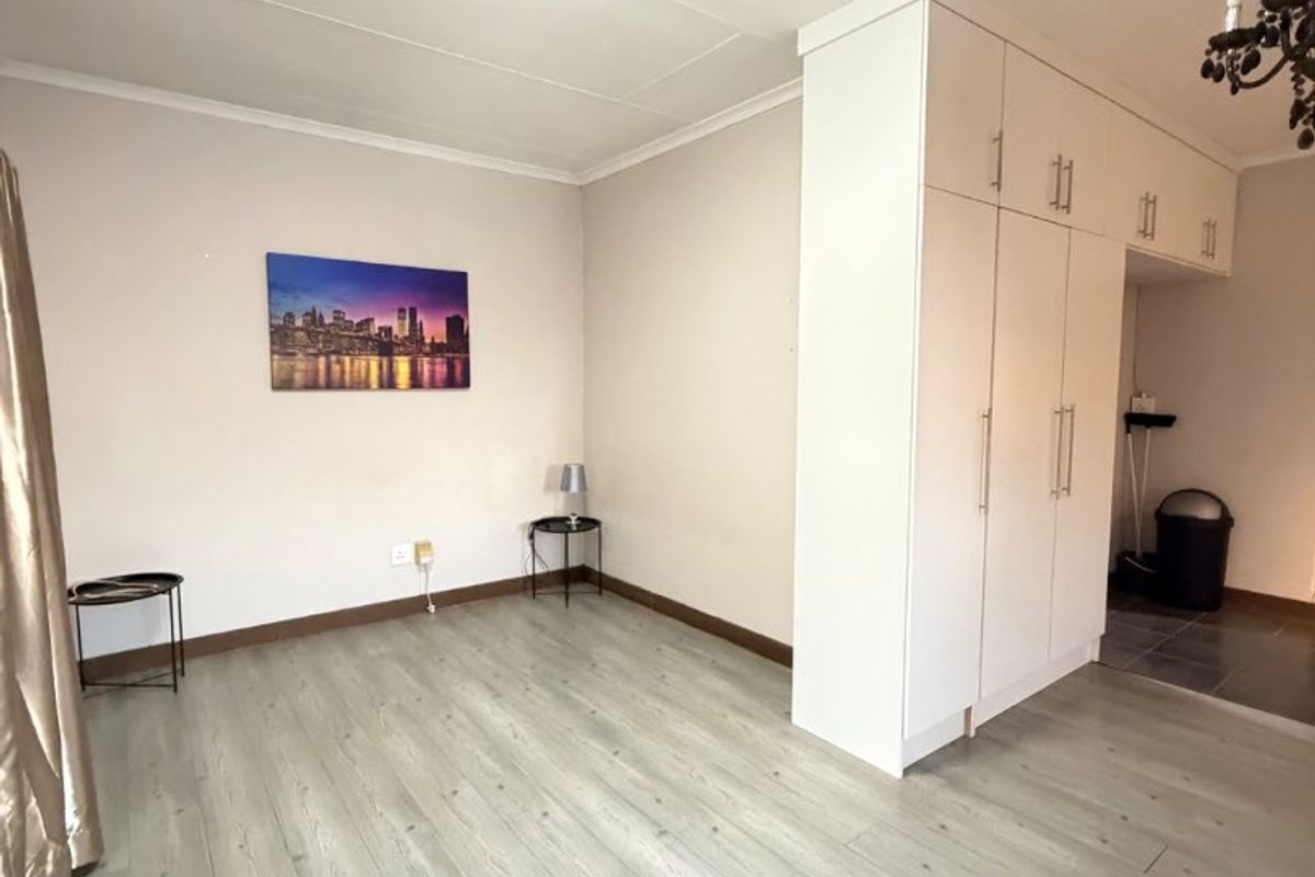 A bright and spacious living area featuring modern laminate flooring and ample built-in cupboard storage, offering a clean and versatile living space.