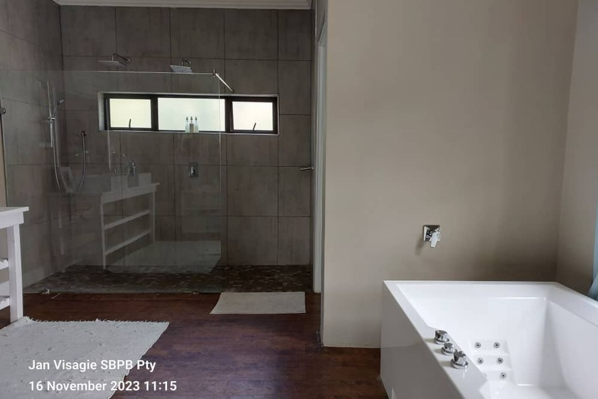 Modern bathroom featuring a large walk-in glass shower with grey tiling and a separate built-in jetted bathtub.