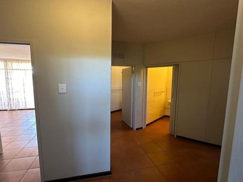 A functional hallway area featuring tiled flooring and built-in storage cupboards, providing access to multiple rooms within the apartment.