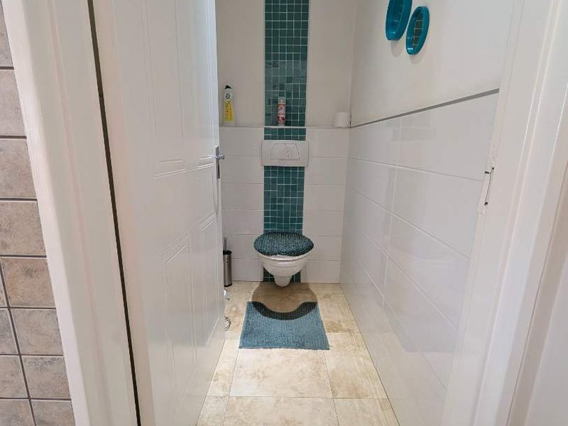 A compact bathroom featuring a wall-mounted toilet with a concealed cistern, accented by a vertical strip of blue mosaic tiles.