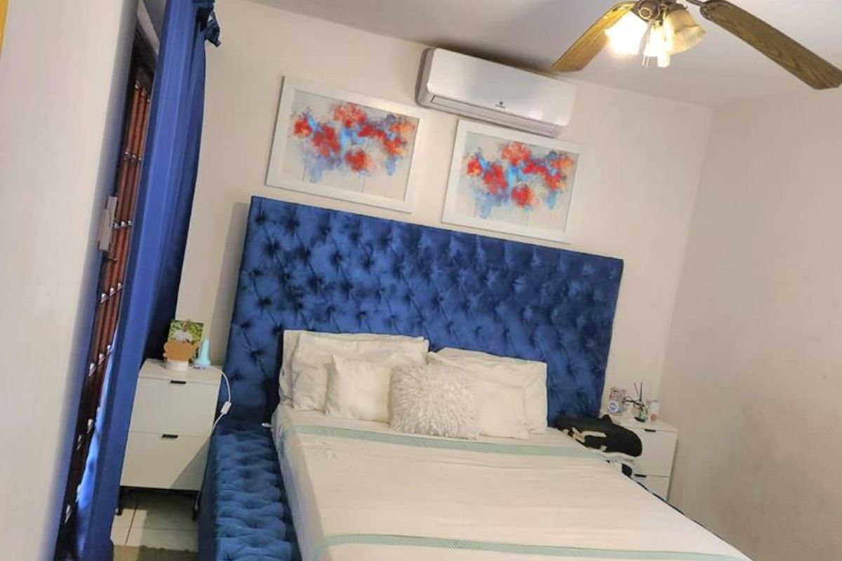 A bedroom featuring tiled flooring, a ceiling fan, and a wall-mounted split-system air conditioning unit.