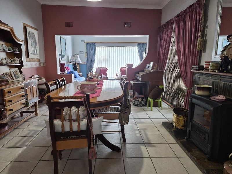 Dining room featuring tiled flooring, a built-in archway connecting to an adjacent living space, and a traditional freestanding fireplace.