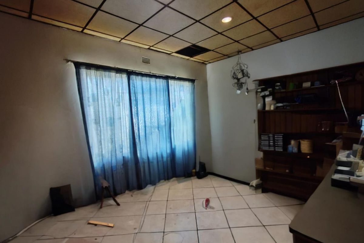 A spacious living area featuring tiled flooring and a drop ceiling, offering a blank canvas for renovation and modernization.