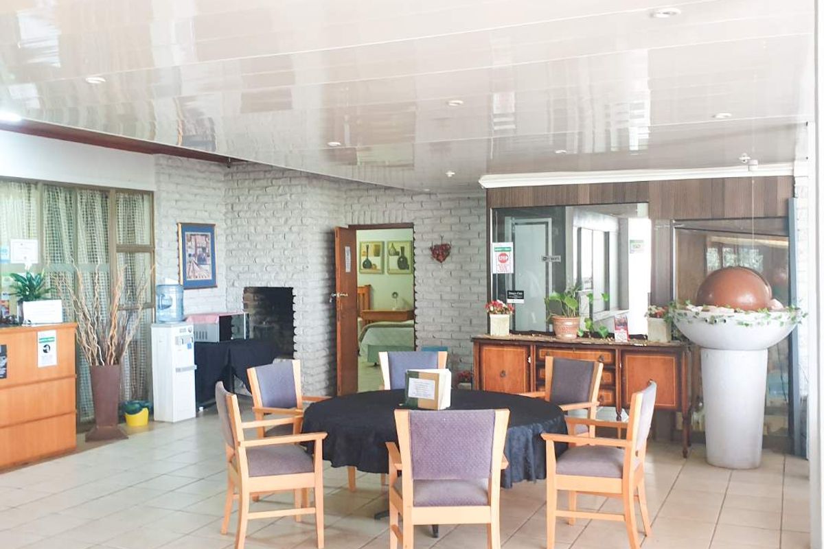 A spacious living area featuring tiled flooring, a brick fireplace, and a glossy ceiling, offering a versatile layout for relaxation or social gatherings.