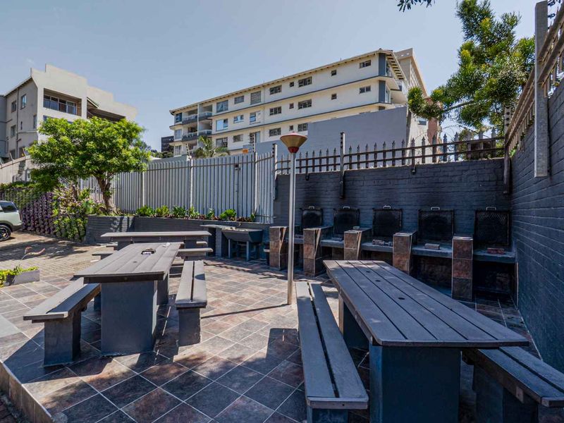 Communal outdoor entertainment area featuring multiple built-in braai stations and paved flooring, suitable for social gatherings within the apartment complex.